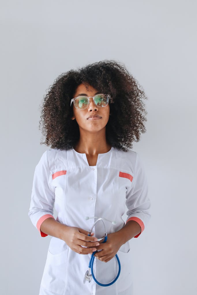 Portrait of a female doctor wearing glasses and holding a stethoscope indoors.